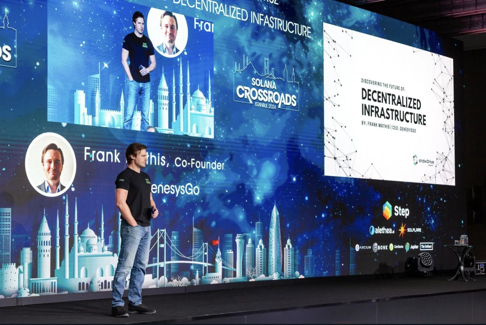 1. Speaker presenting decentralized infrastructure innovations at Solana Crossroads 2024 with GenesysGo branding.